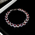 Primo piano del bracciale in zircone con pietra rossa in una scatola di velluto nero - Rosso