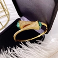 Detailed close-up of golden open bangle with green malachite texture and white zircons - Gold + Green