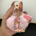 Detail of pink faux fur pom pom and transparent resin letter L with heart sequins - Letter L