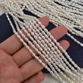 Macro view of multi-strand white freshwater rice pearls held by hand on blue velvet - 3-3.5mm/Approx 37cm / Natural White Strong Light