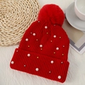 Close-up of red knit beanie with soft faux fur pompom and white pearl embellishments - One Size / Red