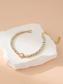 Détail d'un bracelet doré orné de zircons blancs et d'un pendentif en cœur rose - Pentagone Rose