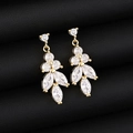 Macro shot of gold-plated leaf earrings with crystal inlay on black leather background - Earrings / Gold Color Earrings
