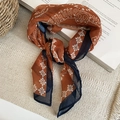 Detailansicht des Paisley-Seidenschals in Karamell und Marineblau auf Vintage-Büchern - Karamell Dunkelblau Kontrast Stil / Orange Paisley