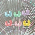 Close-up of translucent colorful resin W-shaped charms on a holographic shell tray - Letter W