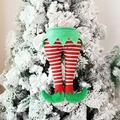 Gambe di elfo di Natale a strisce rosse e bianche appese a un albero di Natale innevato - Stile Elfo Verde