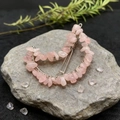 Detail of pink natural crystal stones wrapped on a crescent moon hair clip on rock - Rose Quartz