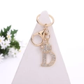 Golden letter D keychain with crown and sparkling crystals on a white display - Letter D / Gold