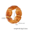 Détail d'un bracelet épais en résine ambrée avec des accents dorés en acier inoxydable poli - Brun (60mm)