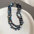 Detailed macro view of irregular blue shell beads and silver metallic spacers on a necklace - Blue