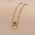 Macro view of a gold-plated letter E pendant necklace with clear sparkling rhinestones - Letter E