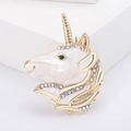 Golden unicorn head brooch with white enamel and iridescent rhinestones on white background - White