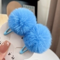 Close-up of blue plush faux fur ball hair clips on a white display card in two pieces - One Pair / Blue