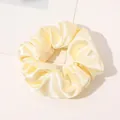 Close-up of a pale yellow silk satin scrunchie with elegant folds and shiny texture - Light Yellow