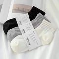 Three pairs of cotton blend ankle socks in black, grey, and white with paper bands - One Size / White