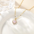 Macro detail of heart-shaped gold necklace with pink zircon and white pavé setting - July - Pink