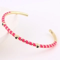 Detail of gold-plated bangle with magenta stripes and black enamel circular accents - Rose Red