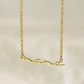 Close-up of a gold-plated necklace with a cursive Mama script pendant on a soft background - Gold