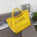 Detail of a yellow hollow silicone basket bag with geometric patterns and round handles - Small Yellow