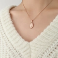 Collana con medaglia ovale in oro rosa con ritratto femminile su maglione bianco - Oro rosa