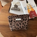 Détail d'une pochette vintage en velours côtelé léopard avec étiquette sur table en bois - Léopard Café