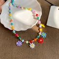Collar de cuentas de colores con dijes de margaritas sobre una bandeja de cerámica - Colorido