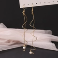 Detailed shot of golden spiral drop earrings featuring elegant pearls on black silk - KC Gold (12458)