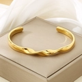 Macro-opname van 18K vergulde gedraaide golfarmring op een elegante zijden sieradendoos - Gouden Stijl (KB202831-SP)