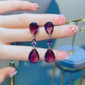 Close-up of elegant triple-tier purple pear-cut drop earrings in a silver-toned setting - Purple Zirconia