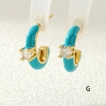Macro shot of C-shaped blue enamel gold earrings with a sparkling round zircon stone - Lake Blue