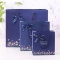 Tre dimensioni di sacchetti regalo blu scuro con motivi floreali e fiocchi di raso - Grande
