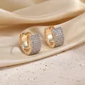 Detail of gold hoop earrings with pavé-set zircons on a textured stone and silk background - B6-02 Simple Two Row Pave Huggie