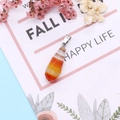 Macro detail of faceted teardrop natural agate pendant with silver bail on decorative card - 10x28mm / Red Agate