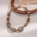 Detail von grauen Glitzer-Acrylperlen und Gold-Abstandshaltern an einer Retro-Kette - Grau