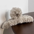 Detail shot of plush faux fur shark hair claw clip in beige on a wooden background - Beige