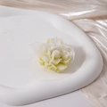 Detail of flower-shaped aromatherapy candle in cream white on a champagne satin background - Yellow-Green
