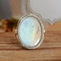 Vintage oval moonstone ring with a silver band displayed on a rustic wooden surface - US 6 / Antique Silver
