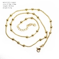 Close-up of golden copper ball chain necklace coiled on white background - Ball Chain