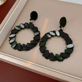 Detail of geometric resin hoop earrings with black and green beads on a jewelry tray - Black-Green