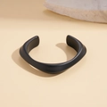 Close-up van een matzwarte acryl armband met een onregelmatig golvend sculpturaal ontwerp - Golvende Sculptuur Stijl (HB4923-1)