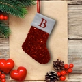 Mini calza di Natale rossa con paillettes e lettera B su tavolo con decorazioni - Lettera B