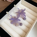 Detail von lila Blumenohrringen aus Harz mit Zirkonia-Perlen in einer Schmuckschatulle - Lila