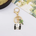 Close-up of golden enamel panda and bamboo keychain with polished metal finish - Peeking Panda and Bamboo