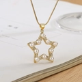 Chic gold star pendant necklace with pearl and zircon inlay on an open book page - Star Pendant / Gold