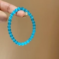 Detail shot of a blue cat-eye stone beaded bracelet showing optical effects on hand - 6mm Bead Diameter / Blue