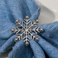 Detailed view of a silver snowflake napkin ring with rhinestones on a blue linen napkin - Silver Style (Z1259-SI) / Silver