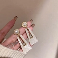Dettaglio macro di orecchini geometrici con resina marmorizzata e decoro perle - Marmo Bianco con Perla (8#)