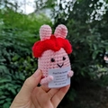 Makroaufnahme einer rosa Häkel-Hasenpuppe, die eine Motivationskarte in der Hand hält - Rosa Häschen