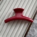 Détail macro d'une pince à cheveux rouge arquée de 11 cm sur un plateau de présentation - Bordeaux