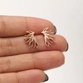 Rose gold wing earrings in polished stainless steel held for size perspective - Tree Branch / Rose Gold